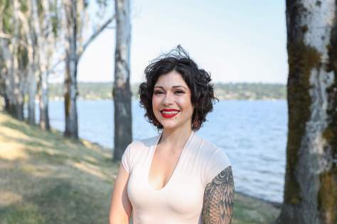 Photo of Carmen Rivera standing in front of a tree-lined body of water.