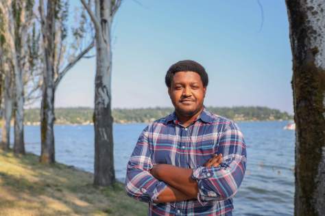 Photo of Cliff Cawthon standing in front of a tree-lined body of water.